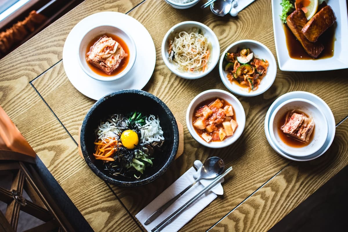 A full table of banchan side dishes and stone-pot bibimbap at Young Dong Tofu